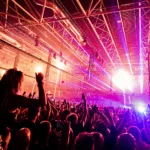 La foule en liesse devant la scène lors d’un événement A State Of Trance à l’Ahoy Rotterdam, sous un impressionnant dispositif de lumières et de lasers.