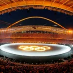 Stade olympique bondé lors des Jeux Olympiques d'Athènes 2004, avec les anneaux olympiques illuminés au centre de l'arène.