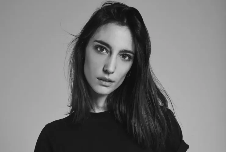 Portrait en noir et blanc d'Amelie Lens, DJ et productrice belge, avec un regard intense et des cheveux mi-longs, vêtue d'un haut noir sur fond neutre.