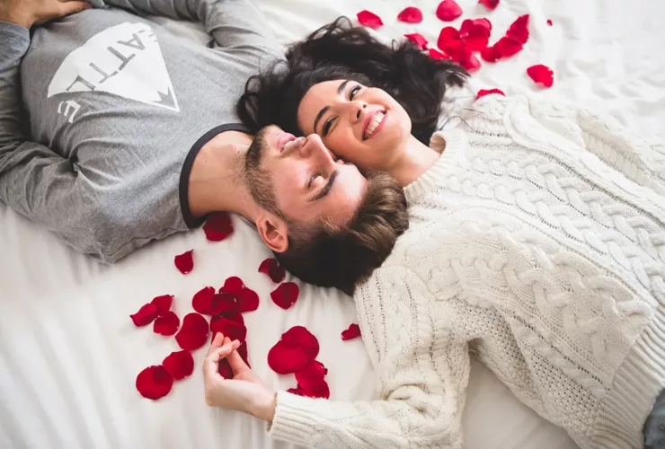 Couple couché sur la tête de lit avec la tête entourée de pétales de rose. Illustration pour notre playlist Trance & Progressive spéciale Saint-Valentin.