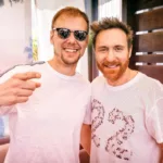Armin van Buuren et David Guetta posant ensemble, souriants, avec Armin portant des lunettes de soleil.