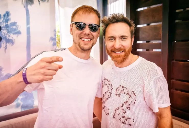 Armin van Buuren et David Guetta posant ensemble, souriants, avec Armin portant des lunettes de soleil.