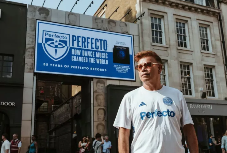 Paul Oakenfold posant devant le Karma Sanctum Hotel, à Soho (Londres), devant une affiche célébrant les 35 ans de Perfecto Records et le documentaire "Perfecto: How Dance Music Changed the World".