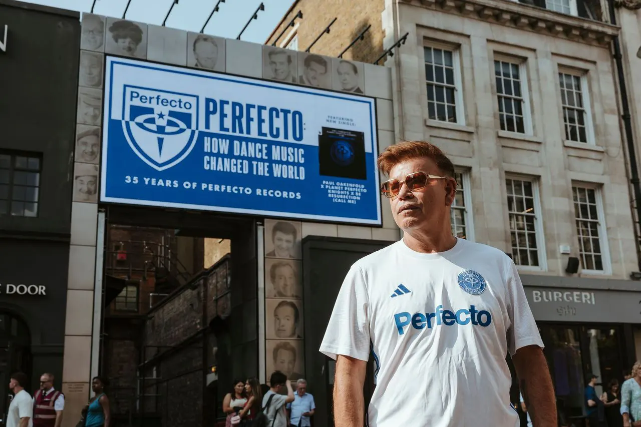Paul Oakenfold posant devant le Karma Sanctum Hotel, à Soho (Londres), devant une affiche célébrant les 35 ans de Perfecto Records et le documentaire "Perfecto: How Dance Music Changed the World".