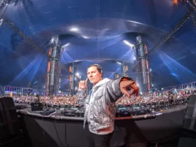 Tiësto sur scène lors d’un DJ set à grande échelle, devant une foule massive.