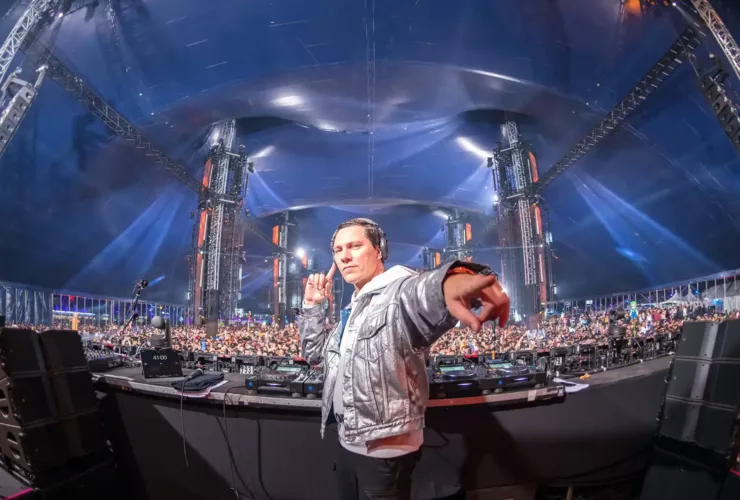 Tiësto sur scène lors d’un DJ set à grande échelle, devant une foule massive.