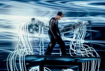 Anyma sur scène devant son setup futuriste, entouré de câbles lumineux et d’écrans.