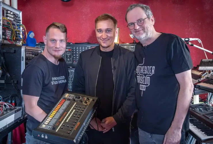 Paul van Dyk posant au centre d’un studio, aux côtés de deux personnes, avec son Roland TR-808.