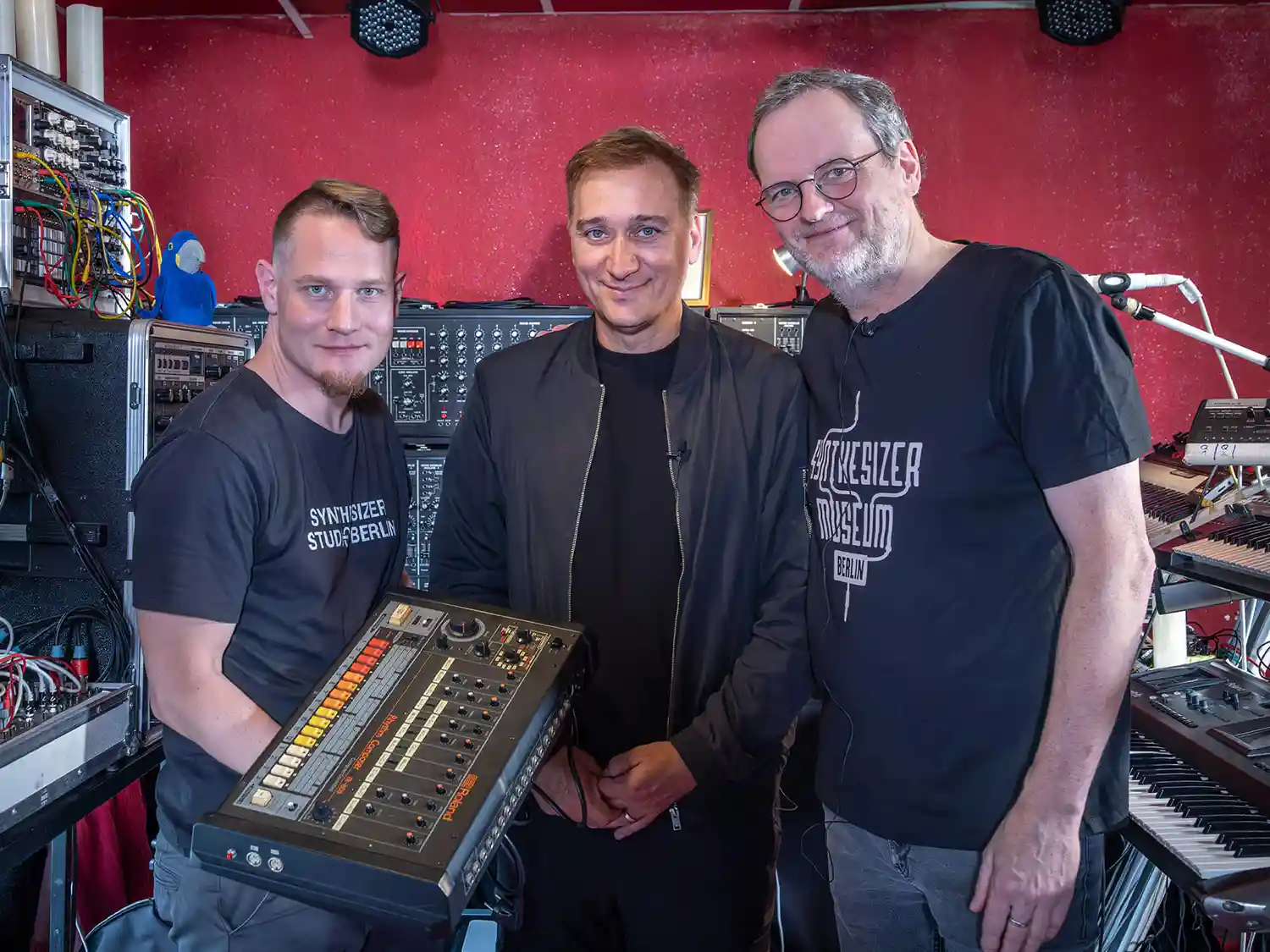 Paul van Dyk posant au centre d’un studio, aux côtés de deux personnes, avec son Roland TR-808.
