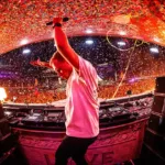 Armin van Buuren sur la scène principale de Tomorrowland, bras levés, sous une pluie de confettis et de lumières flamboyantes.