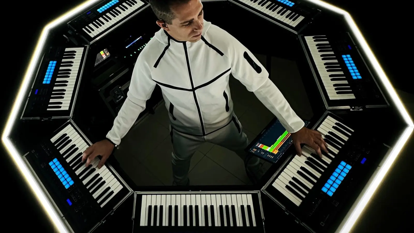 Giuseppe Ottaviani entouré de son dispositif scénique OTTAGON, un setup octogonal composé de claviers et contrôleurs lumineux.
