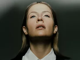 Portrait de Charlotte de Witte, regard tourné vers le haut, éclairée par une lumière contrastée sur fond sombre.