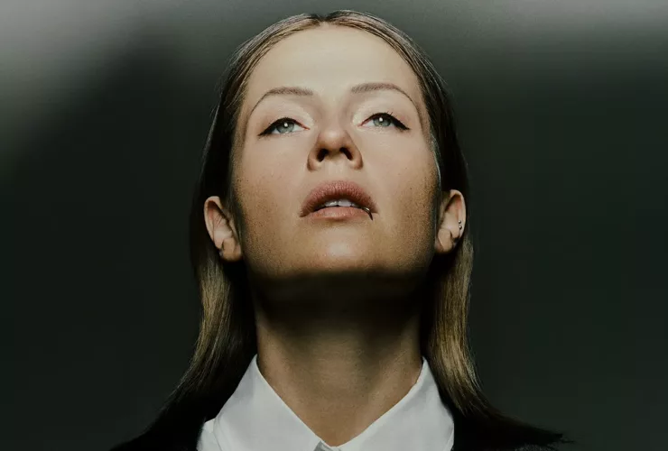 Portrait de Charlotte de Witte, regard tourné vers le haut, éclairée par une lumière contrastée sur fond sombre.
