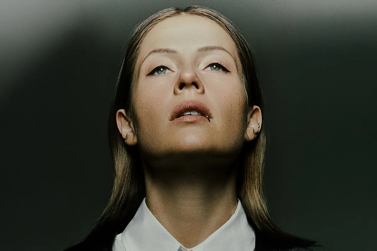 Portrait de Charlotte de Witte, regard tourné vers le haut, éclairée par une lumière contrastée sur fond sombre.