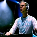Armin van Buuren en DJ set au début des années 2000, concentré derrière ses platines sous une lumière bleue en club.