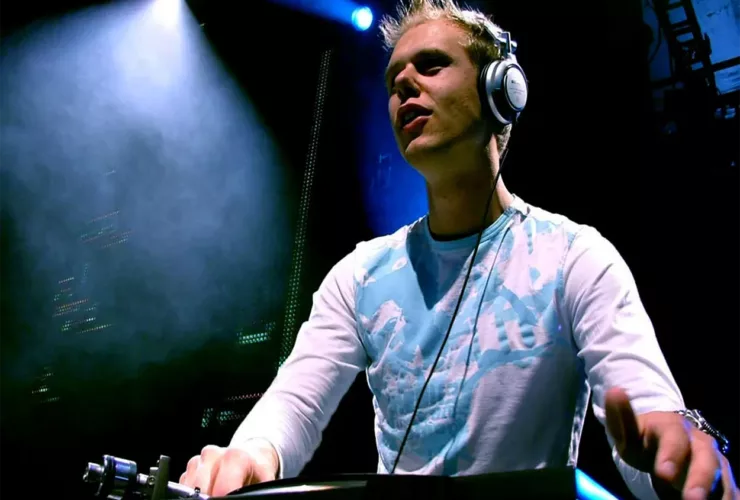 Armin van Buuren en DJ set au début des années 2000, concentré derrière ses platines sous une lumière bleue en club.