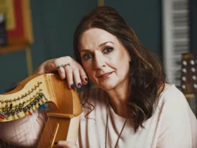 Moya Brennan posant avec une harpe, dans un environnement musical en studio.