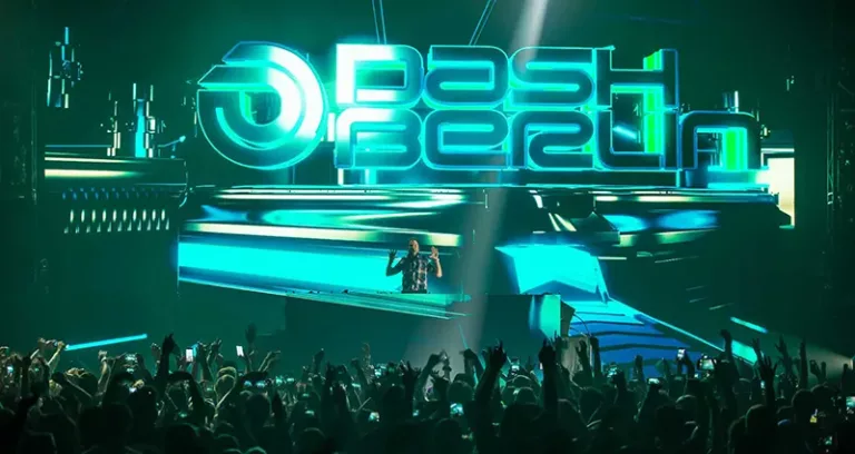 Jeffrey Sutorius sur scène sous l'alias Dash Berlin devant un immense écran lumineux affichant le logo du projet, face à une foule levant les bras pendant le concert.