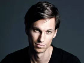 Portrait de Menno de Jong sur fond sombre, vêtu d’un t-shirt noir, regard fixé vers l’objectif avec une expression calme et déterminée.