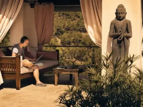 Paul van Dyk est assis avec un ordinateur portable et un casque audio dans un espace de détente du Château Bonheur Musique, avec vue sur la nature et une statue de Bouddha à proximité.