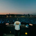 Tiësto joue face à une foule immense lors de son set à Silverworks Island en 2026, au coucher du soleil, derrière ses platines.