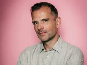 Portrait de Benno de Goeij, membre de Rank 1 et producteur derrière le projet Trance The Quest, posant devant un fond rose.