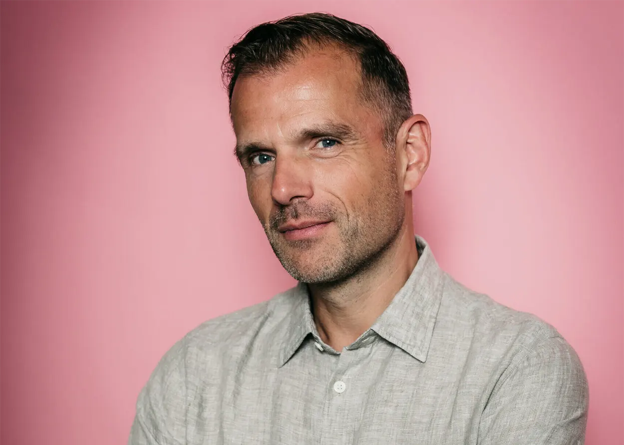 Portrait de Benno de Goeij, membre de Rank 1 et producteur derrière le projet Trance The Quest, posant devant un fond rose.