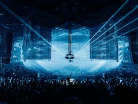 A State Of Trance 2026 au Rotterdam Ahoy, avec une foule immense face à la scène centrale sous des faisceaux laser bleus et de grands écrans suspendus.