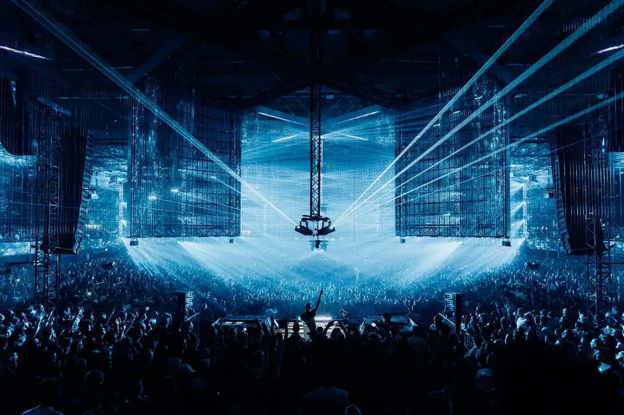 A State Of Trance 2026 au Rotterdam Ahoy, avec une foule immense face à la scène centrale sous des faisceaux laser bleus et de grands écrans suspendus.